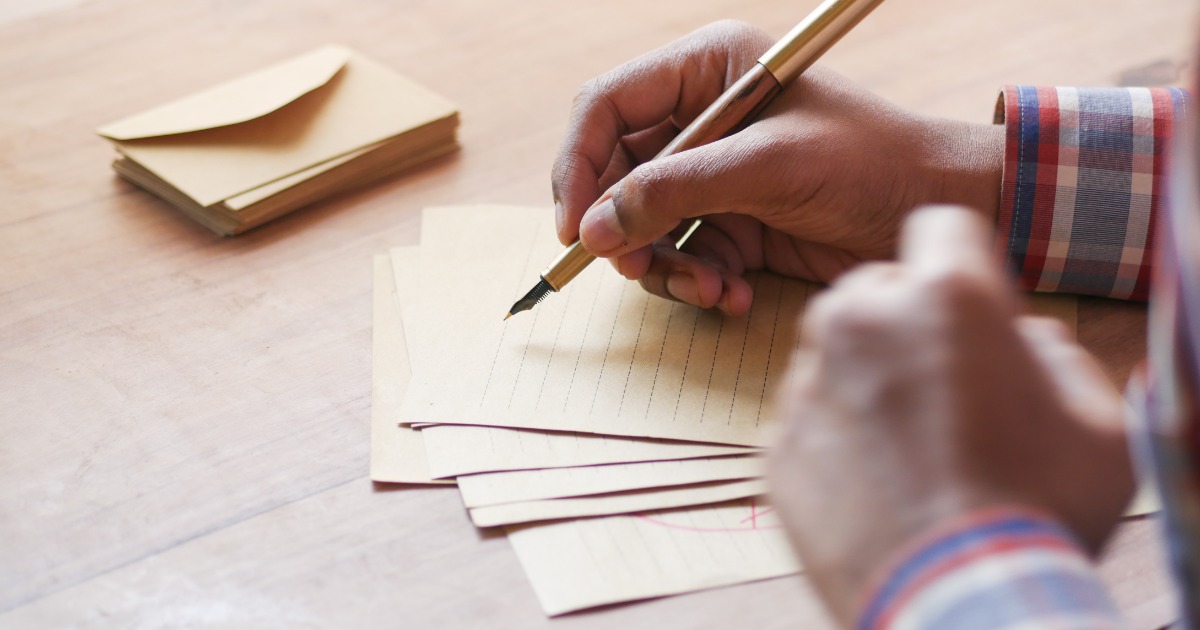 Person writing supportive letter or message to someone in rehab recovery