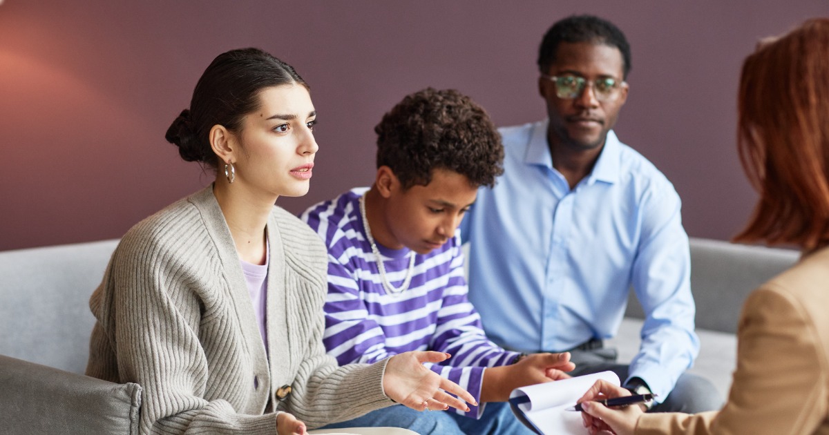 Family meeting with professional interventionist in comfortable office setting discussing addiction treatment options