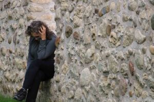 Woman sitting alone at Stone Wall appearing to be in distress or experiencing Mental Health
