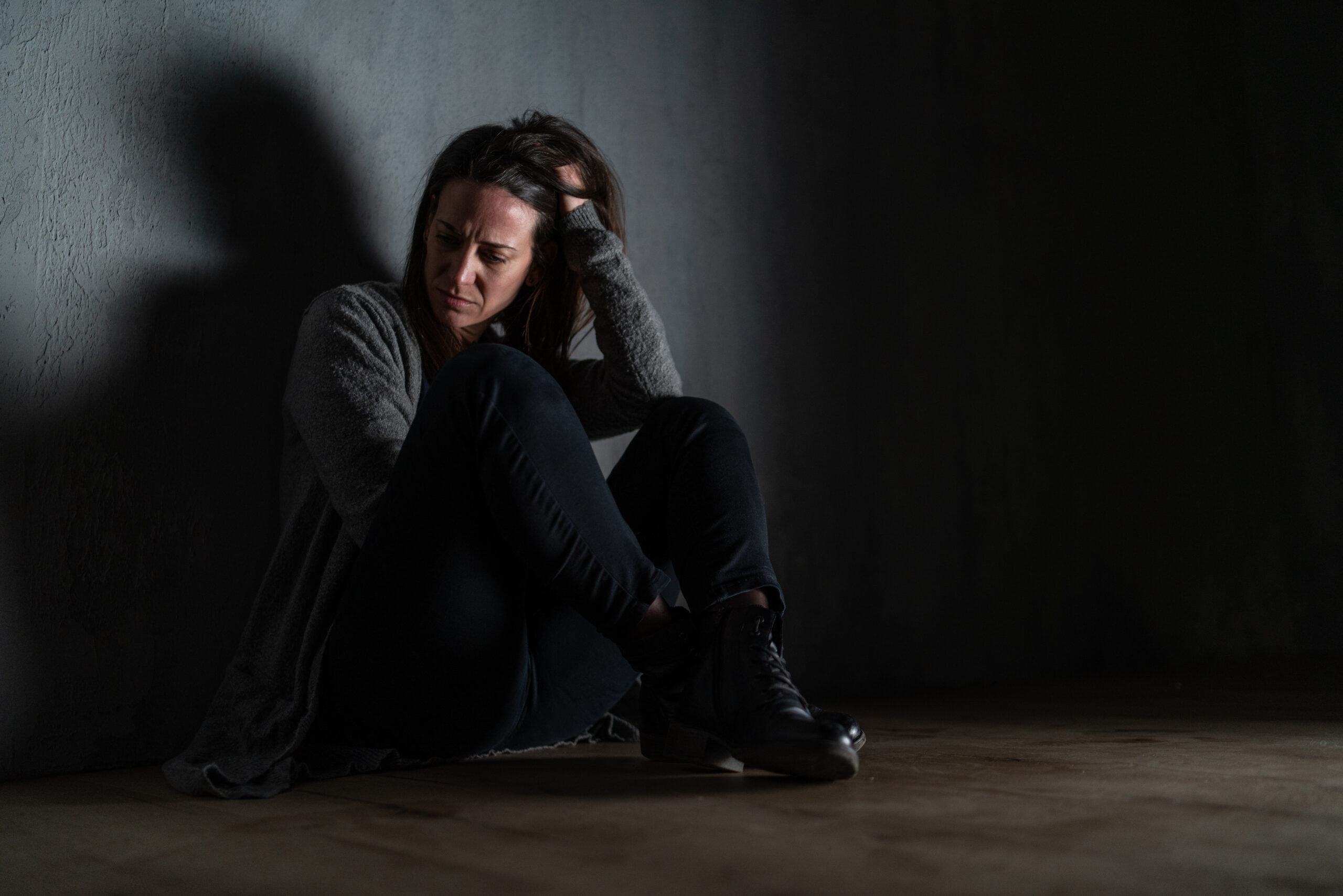 Woman experiencing signs of depression sitting alone in darkness wondering am I depressed
