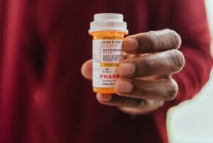 a man holding a bottle of opioids wondering “what is opioid addiction?”