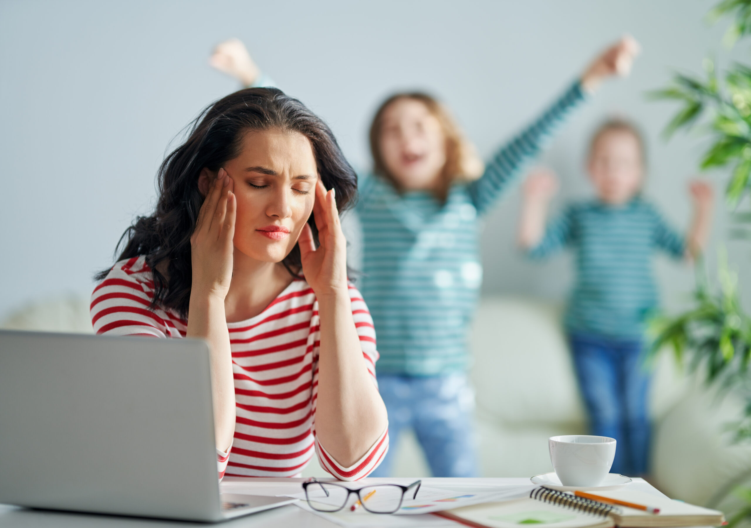 Frustrated adult with ADHD trying to focus while children play in the background