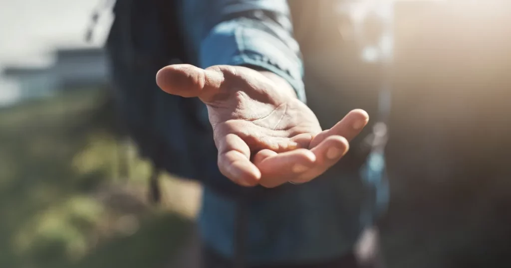 Person extending open hand offering help and support symbolizing mental health assistance and compassionate care
